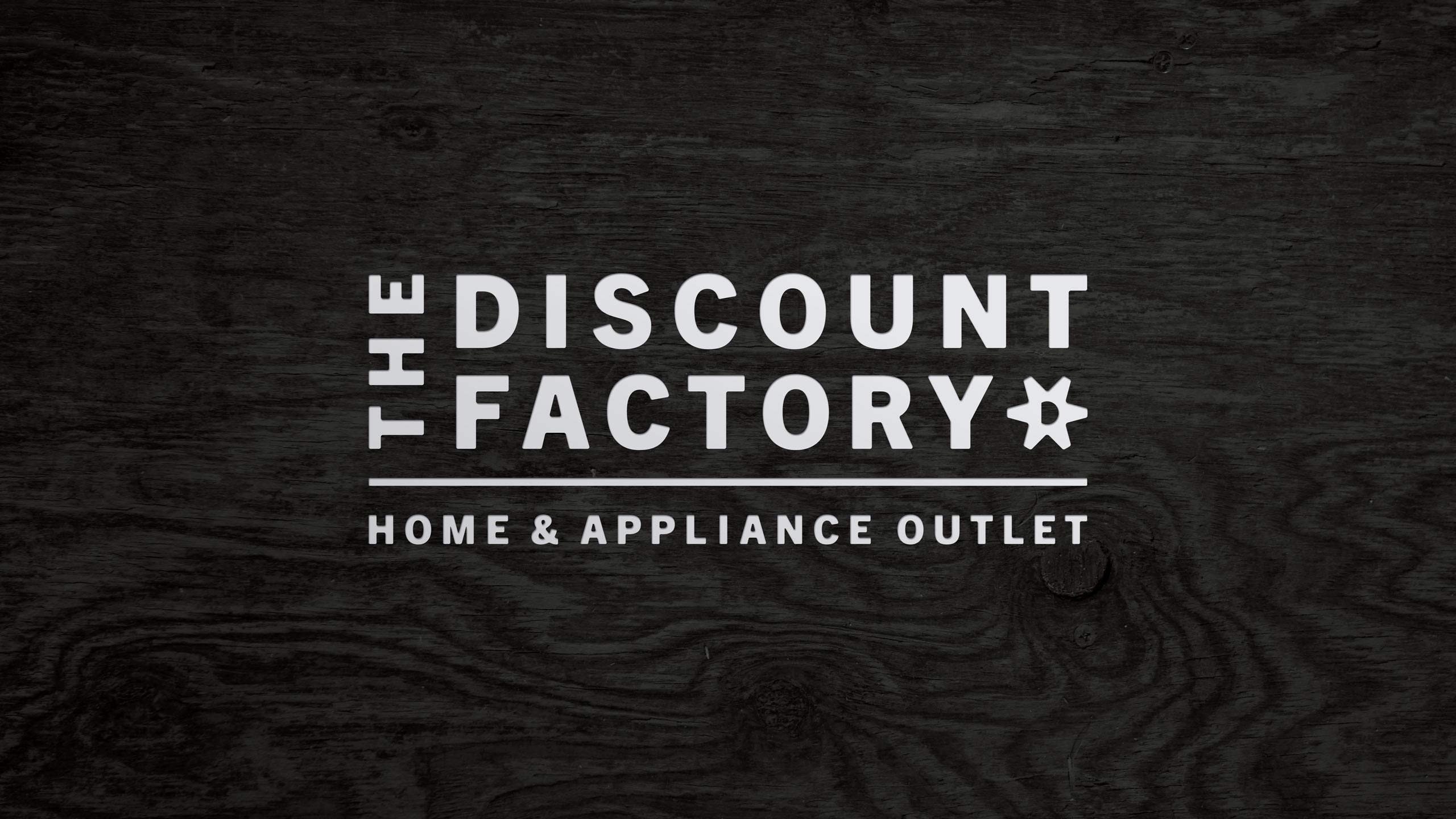 The Discount Factory Home & Appliance Outlet logo reversed out in white on a dark gray woodgrain texture