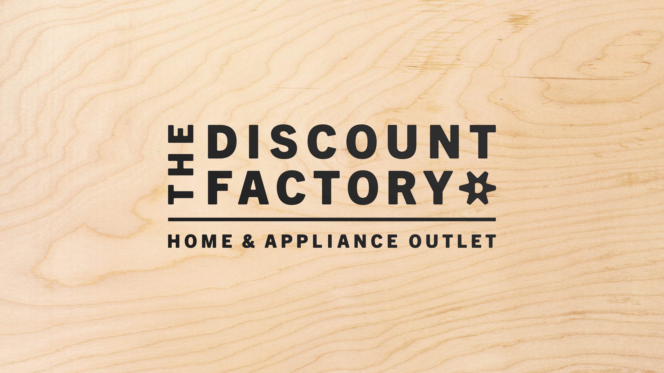 The Discount Factory Home & Appliance Outlet logo in black on a light tan woodgrain texture