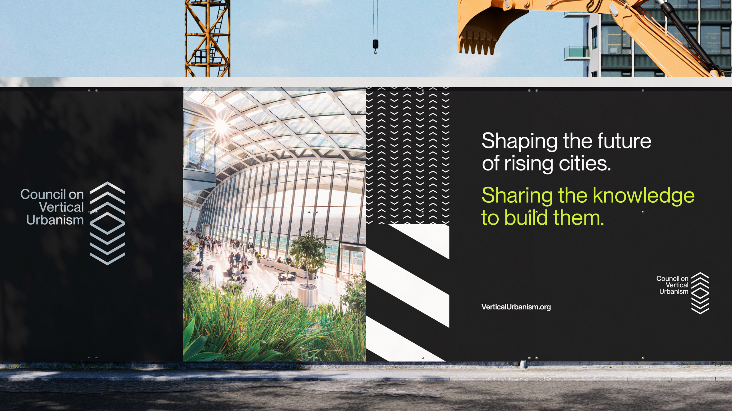 A billboard displays part of a modern glass building and text: "Shaping the future of rising cities. Sharing the knowledge to build them." There is a construction crane behind the wall of billboards.